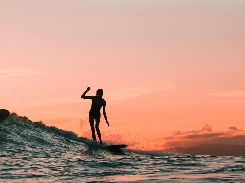 Person feeling energetic and stretching outdoors at sunrise.