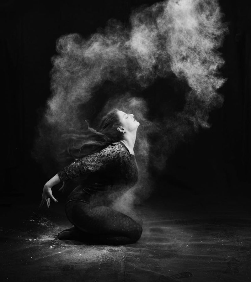Woman performing a dynamic cardio movement in a minimalist dark studio.